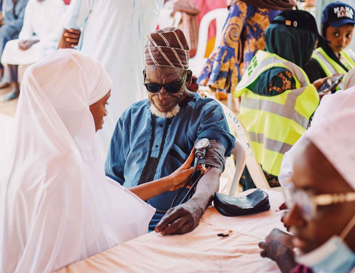 A community health worker conducting visual acuity testing using an eye chart with a community member in a Nigerian village or community health event