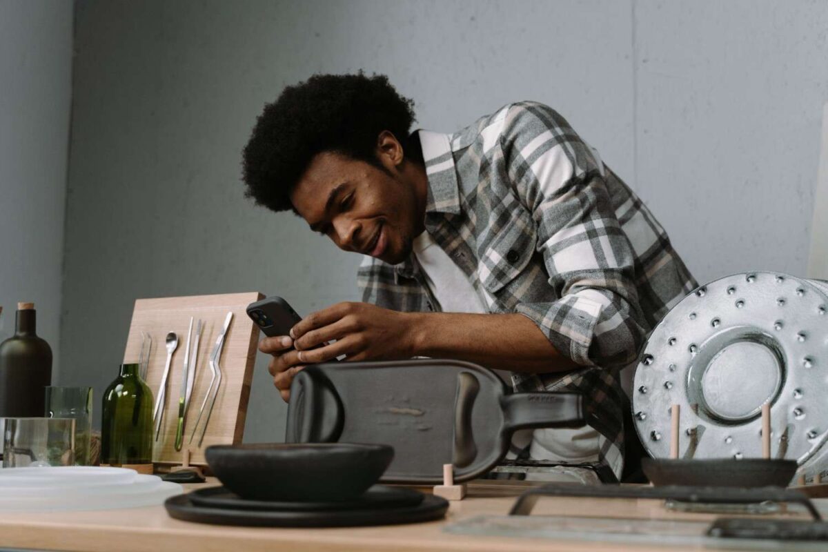 Nigerian community entrepreneur photographing products for an online store or managing e-commerce sales on a smartphone Alt text: e-commerce tools entrepreneurs Nige